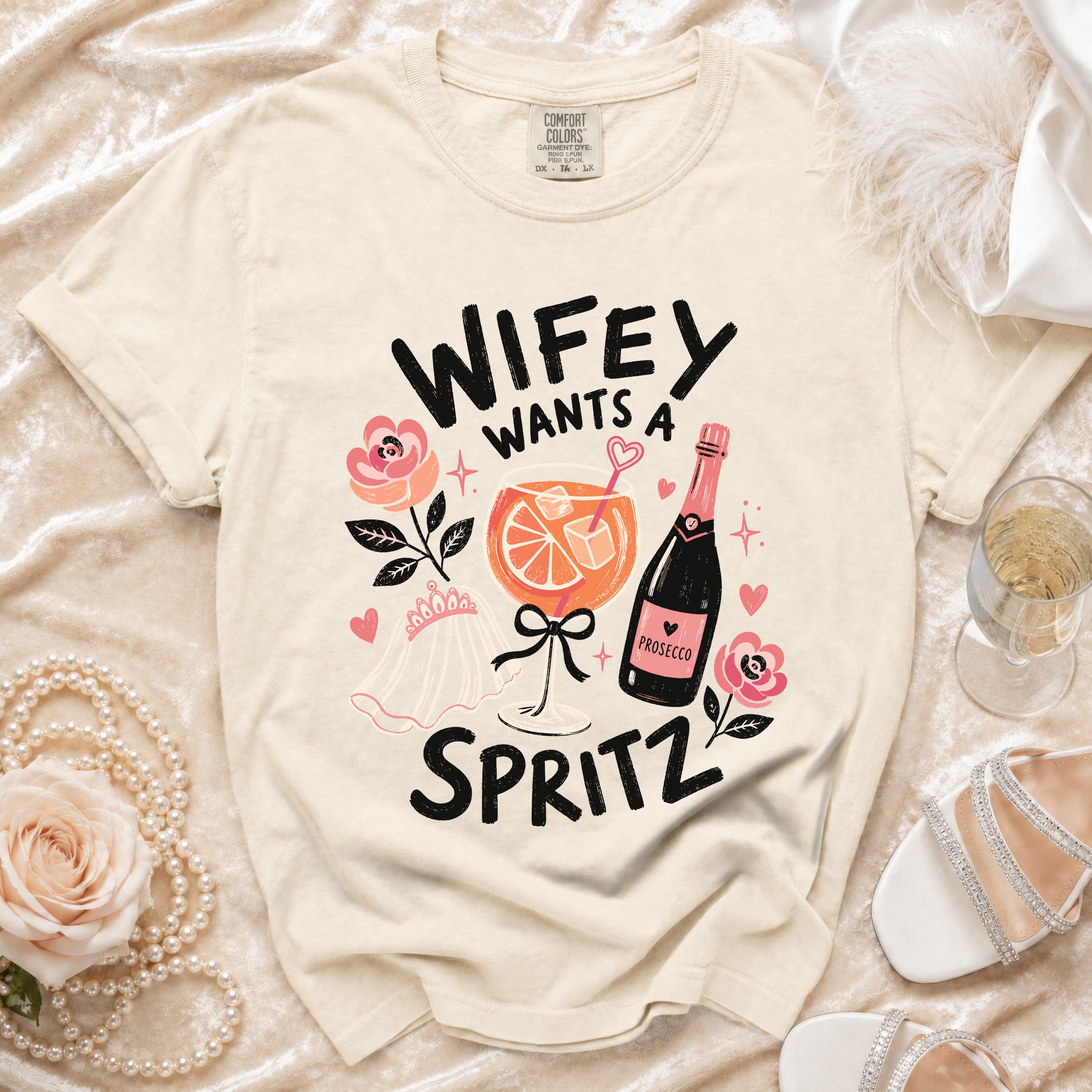 Cream t-shirt with text "Wifey Wants a Spritz" and wedding/drink graphics.