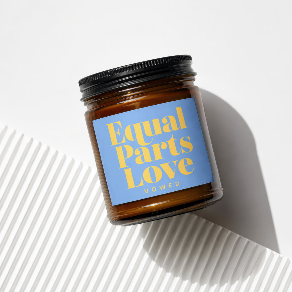 Amber candle in jar with blue label reading "Equal Parts Love Vowed".