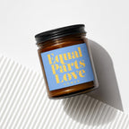 Amber candle in jar with blue label reading "Equal Parts Love Vowed".