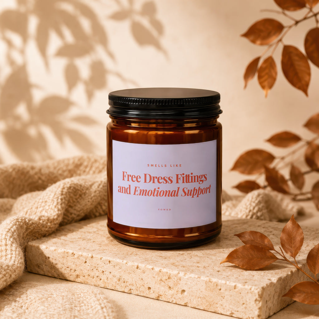 Amber candle with black lid labeled "Free Dress Fittings and Emotional Support".