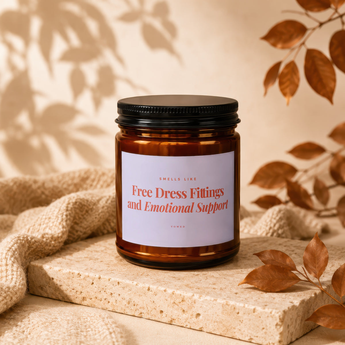 Amber candle with black lid labeled "Free Dress Fittings and Emotional Support".