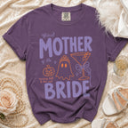 Purple Comfort Colors t-shirt with "Official Mother of the Bride" text and Halloween graphics.