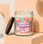 Engagement candle with "Congrats, Lovebirds!" text on a colorful floral label.