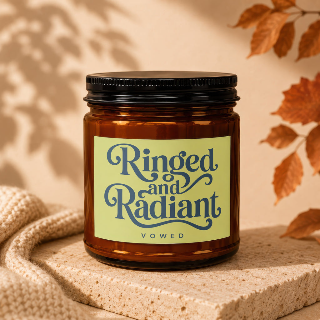 Amber jar candle with "Ringed and Radiant VOWED" label on textured stone.