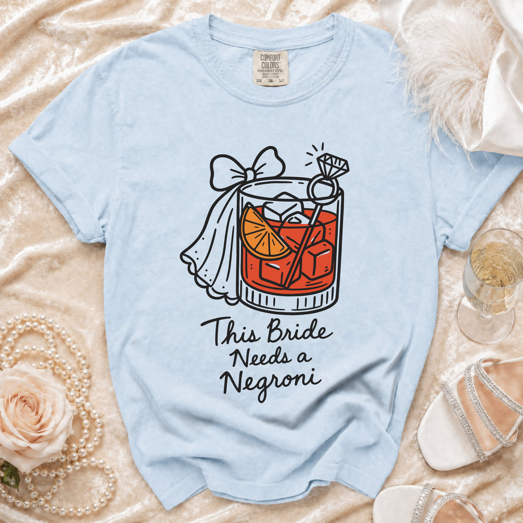 Light blue t-shirt with a graphic of a cocktail and text that reads "This Bride Needs a Negroni."
