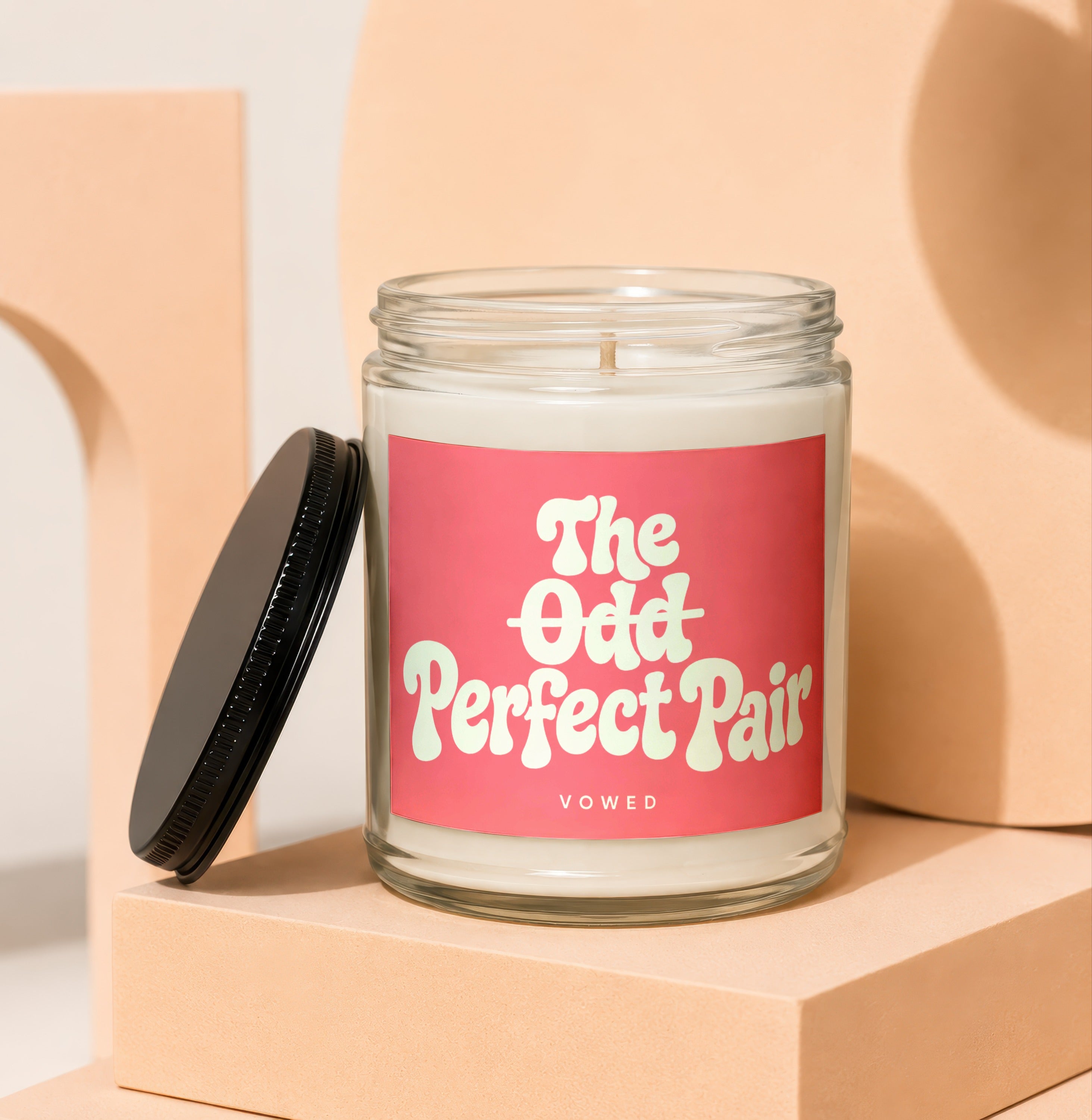 Glass candle with pink label reading "The Odd Perfect Pair" and "VOWED"