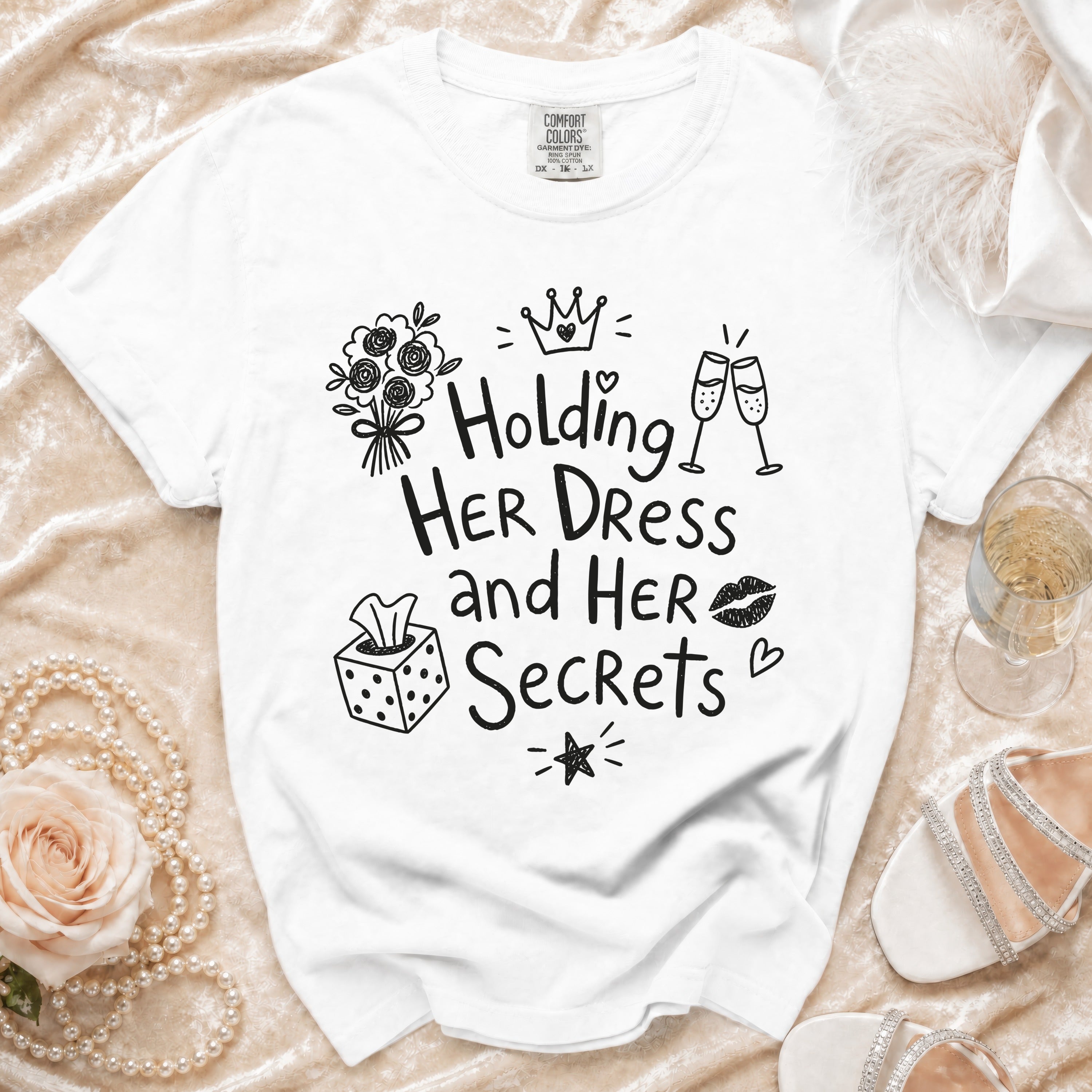 White t-shirt with "Holding Her Dress and Her Secrets" graphic, plus decorative elements.