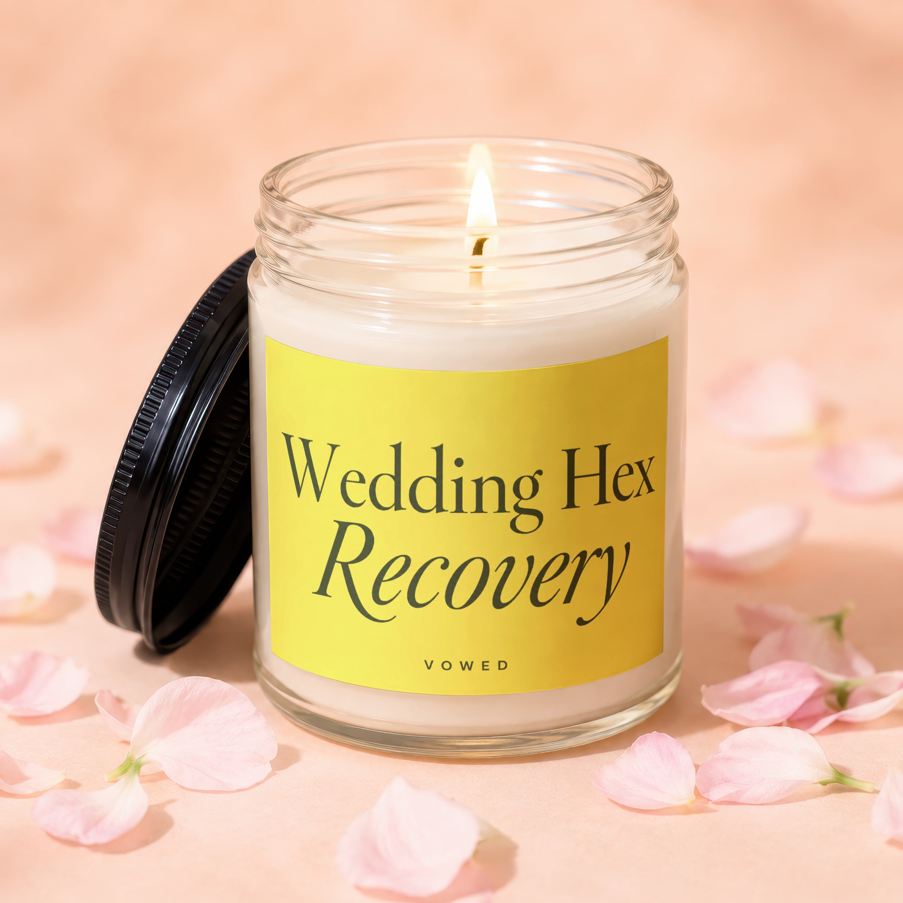 Glass jar candle with lit wick, yellow label reads "Wedding Hex Recovery VOWED".