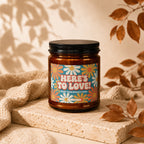 Amber candle with retro flower label reading "HERE'S TO LOVE! FROM YOUR BIGGEST FANS."