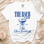 White t-shirt with "The Bach Club" text, cocktail glass, and "Olivia's Bachelorette Charleston, SC" in blue.