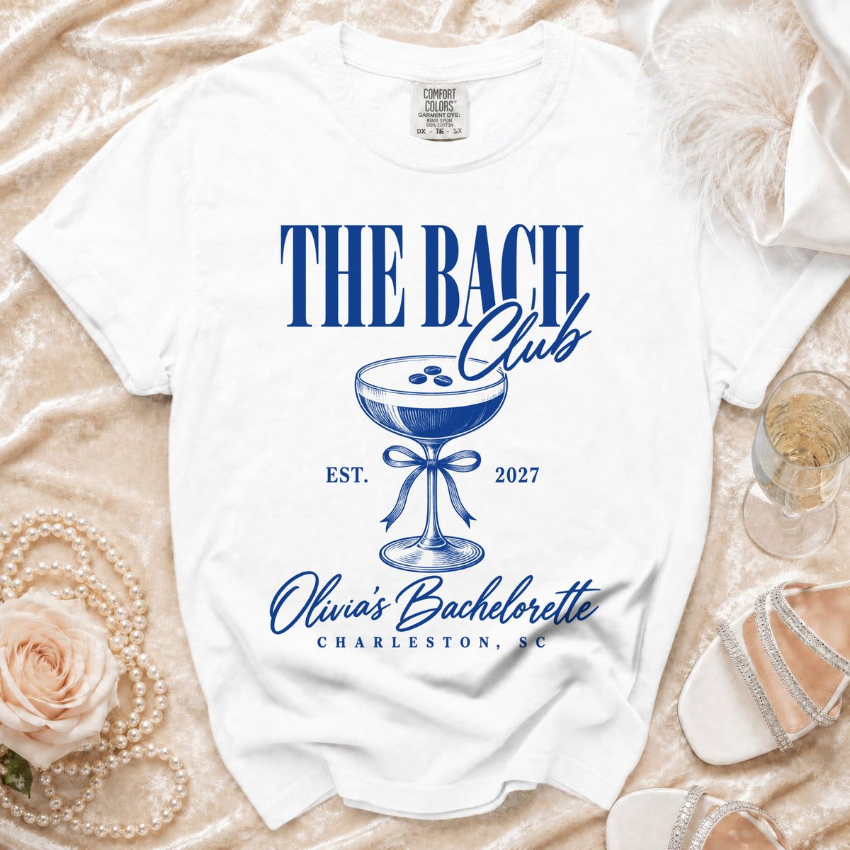 White t-shirt with "The Bach Club" text, cocktail glass, and "Olivia's Bachelorette Charleston, SC" in blue.