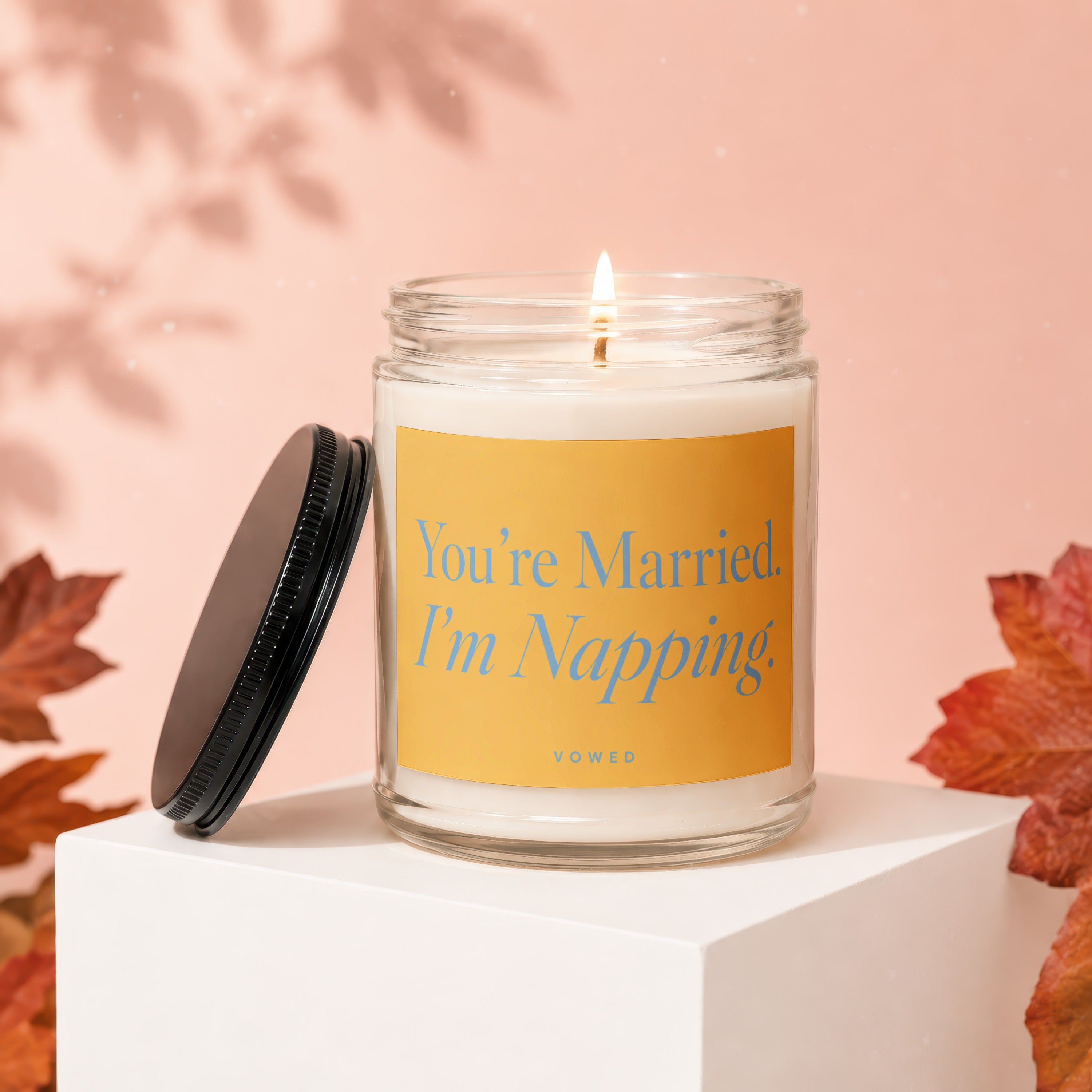Glass candle with lit wick and yellow label saying "You're Married. I'm Napping."