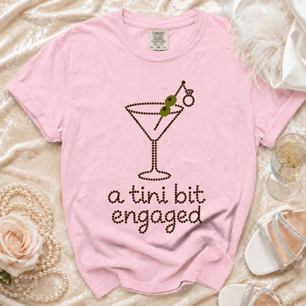 Pink t-shirt with "a tini bit engaged" text and martini glass graphic.