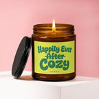 Amber jar candle with a lit flame and a label reading "Happily Ever Cozy VOWED."