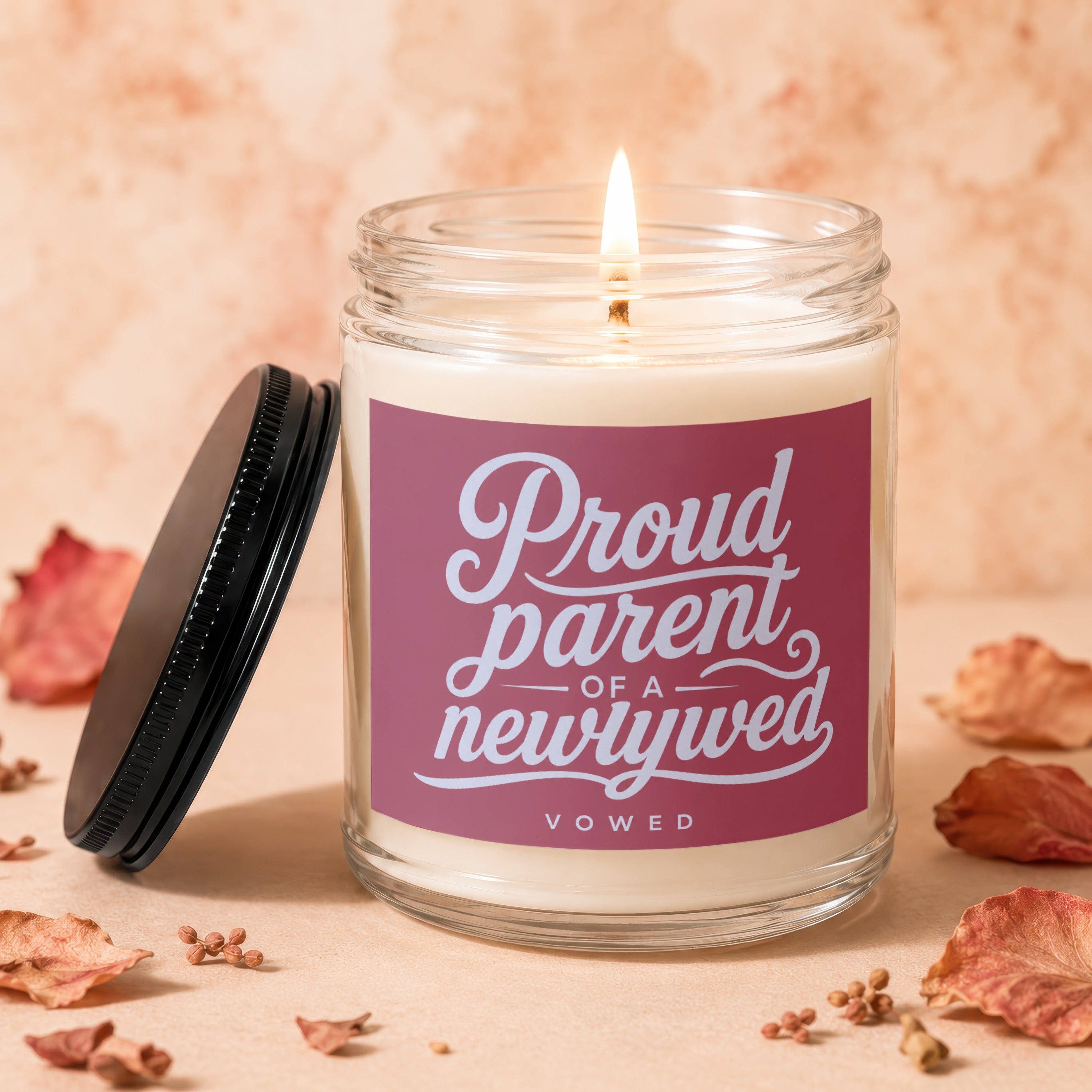 Glass jar candle with pink label reading "Proud parent of a newlywed".