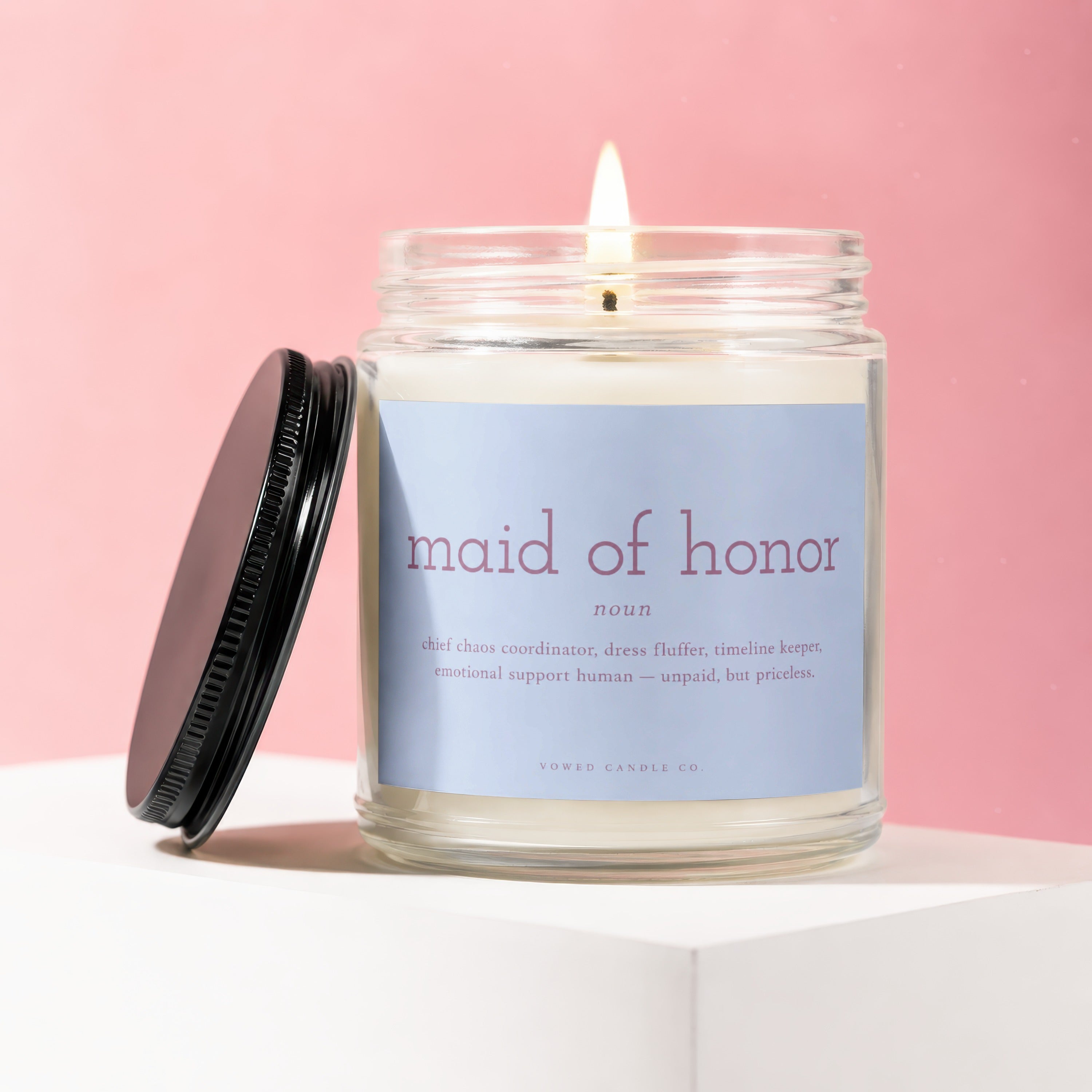 Lit candle in glass jar with "Maid of Honor" label and description.