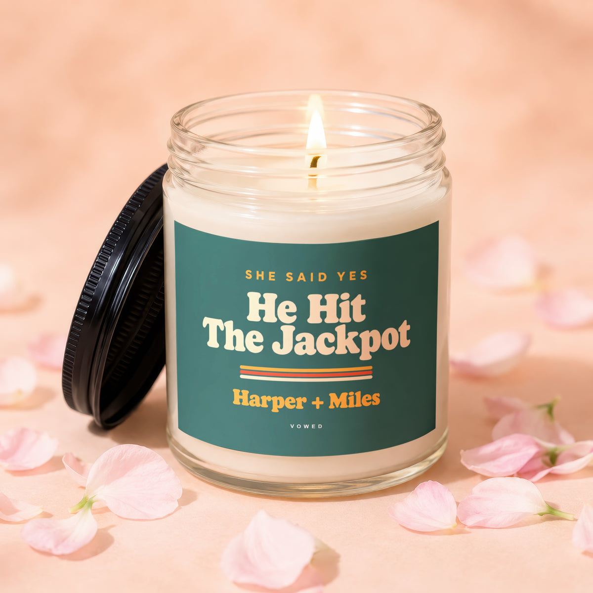 Lit candle with "He Hit The Jackpot Harper + Miles" text on a green label.