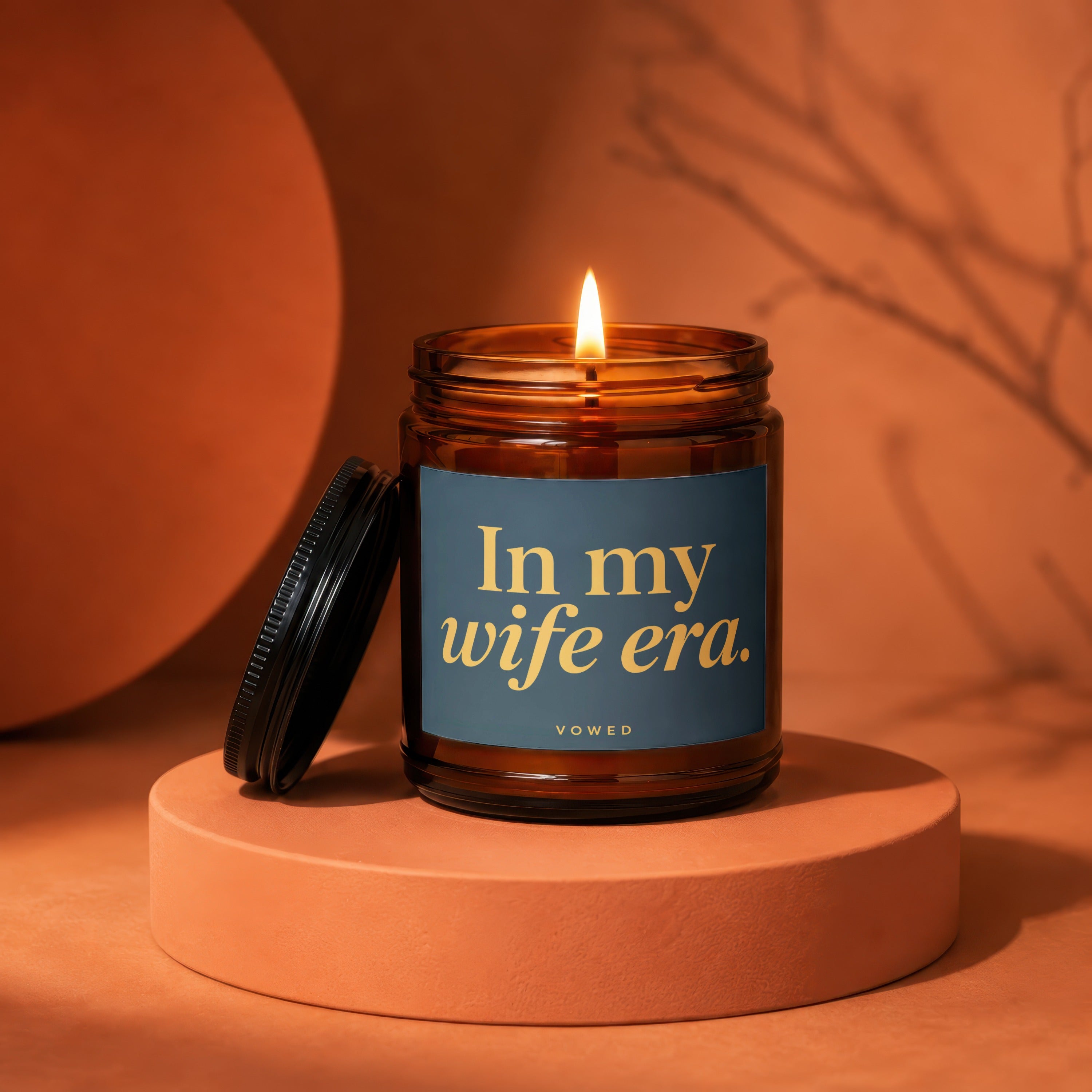 Lit amber jar candle with label reading "In my wife era."