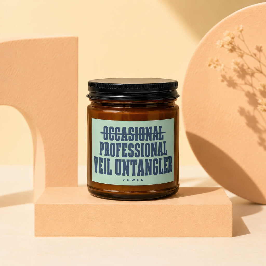 Candle with text "OCCASIONAL PROFESSIONAL VEIL UNTANGLER" on a minimal peach backdrop.