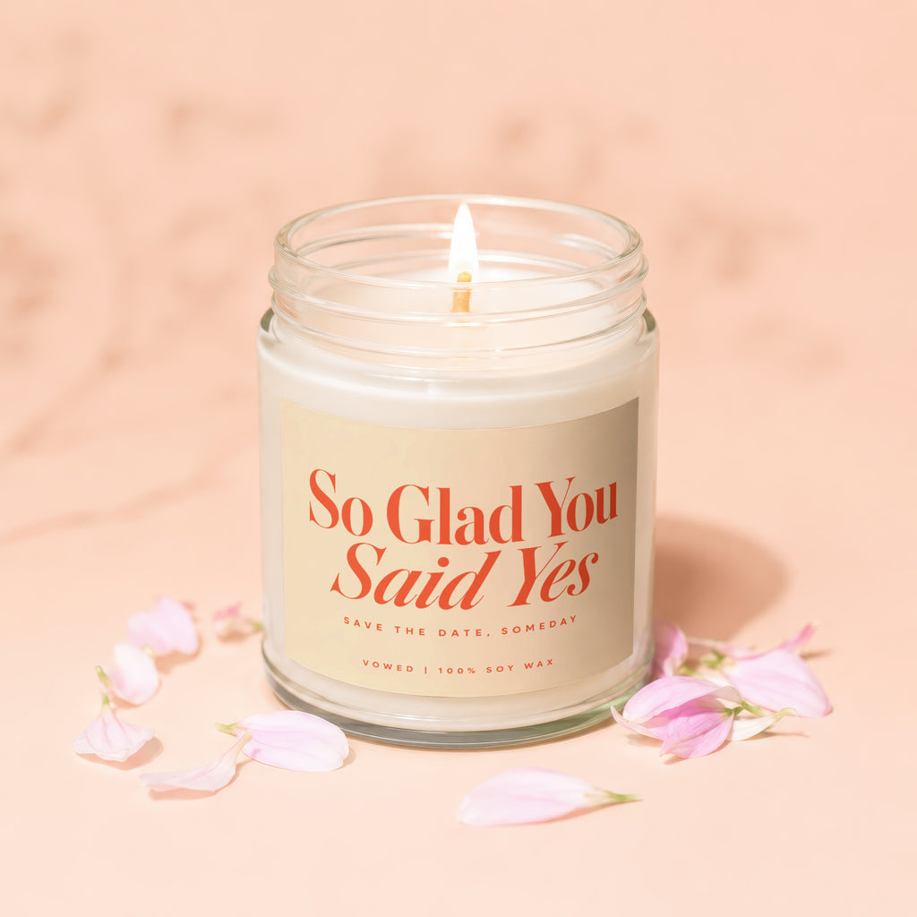 Soy wax candle with "So Glad You Said Yes" text, surrounded by petals.