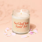 Soy wax candle with "So Glad You Said Yes" text, surrounded by petals.
