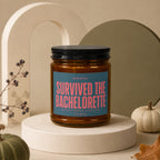 Amber candle with a blue label reading "SURVIVED THE BACHELORETTE VOWED".