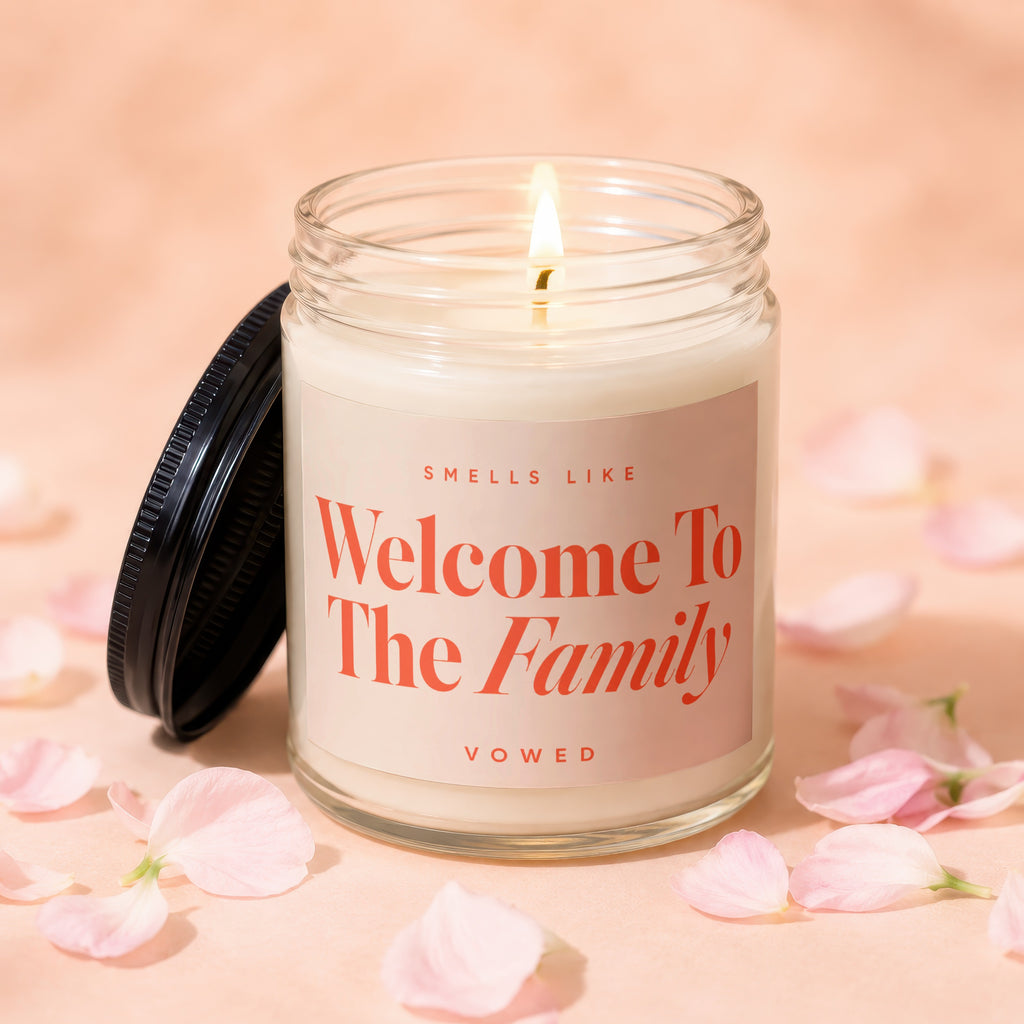 Glass candle labeled "Welcome To The Family" surrounded by pink petals.