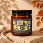 Amber candle with dark lid and label reading "WARNING: THE HONEYMOON NEVER ENDS"