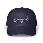 A dark navy blue baseball cap with the word Cowgirl embroidered in white script across the front.
