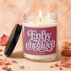 Lit candle in a glass jar with "Fnbdy engaged" text on a pink label.