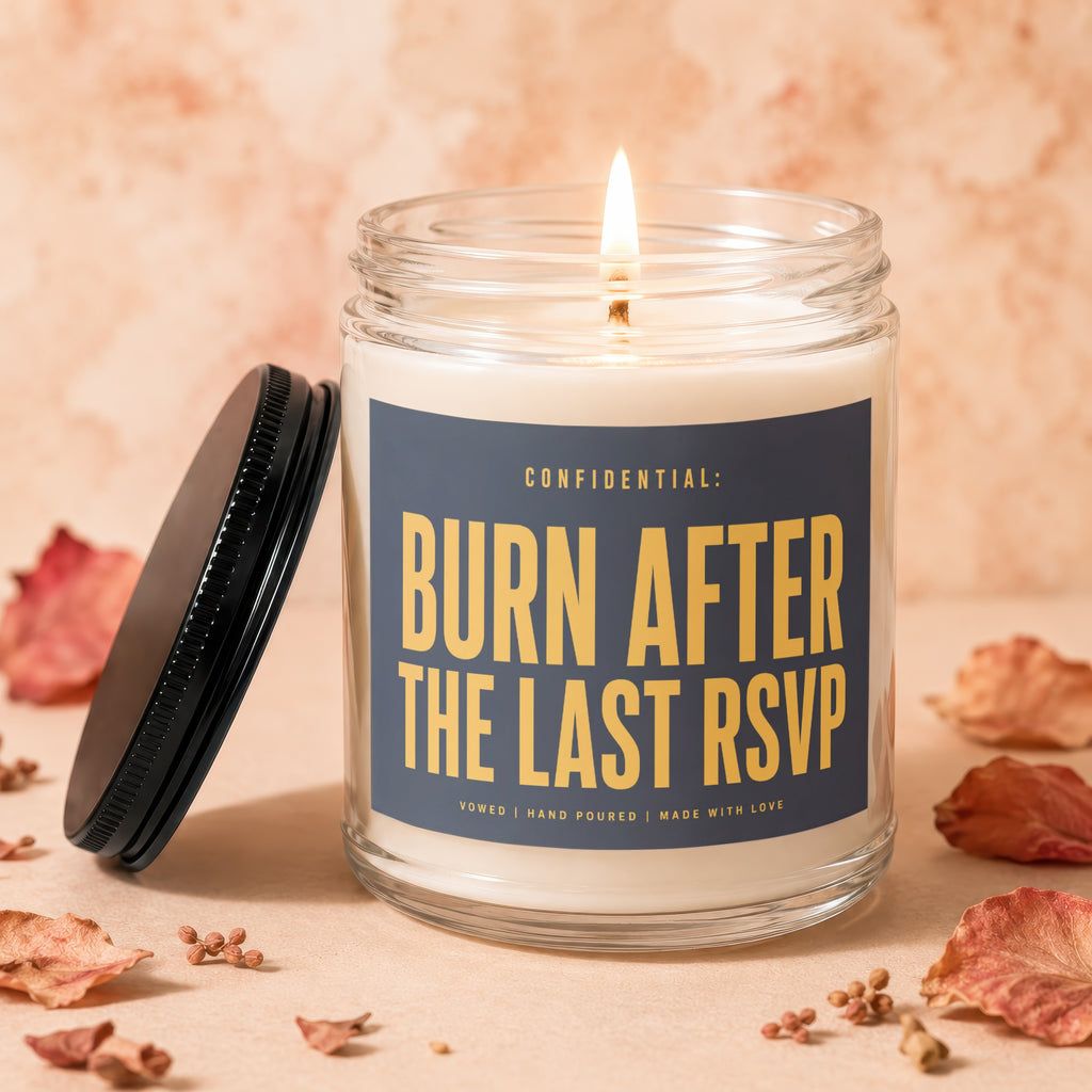 Glass candle with "CONFIDENTIAL: BURN AFTER THE LAST RSVP" text and lit wick.