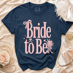 Navy t-shirt with pink "Bride to Be" text, ring, and floral design.