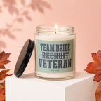 Candle with text "Team bride recruit veteran vowed" on a white pedestal.