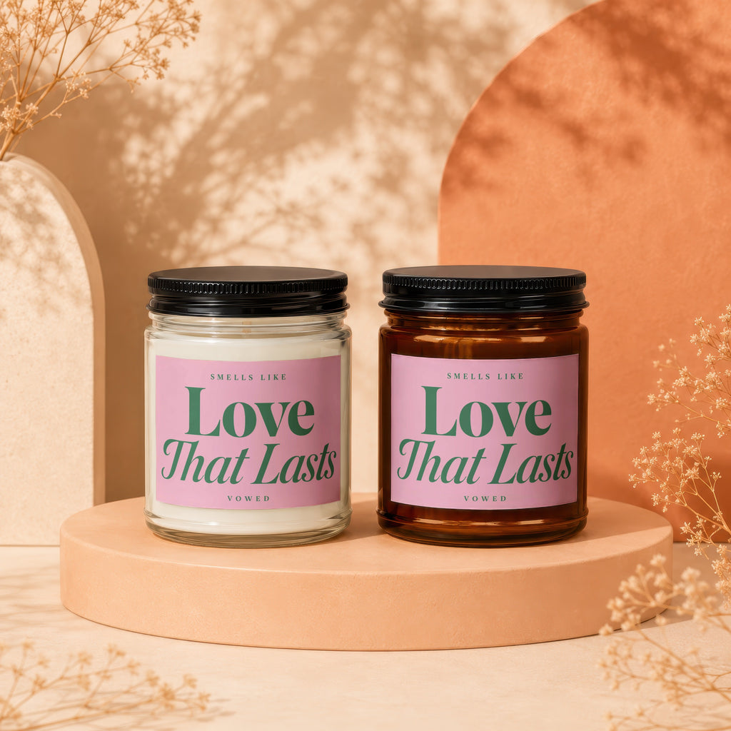 Two candles side-by-side, each with pink labels reading "Love That Lasts".