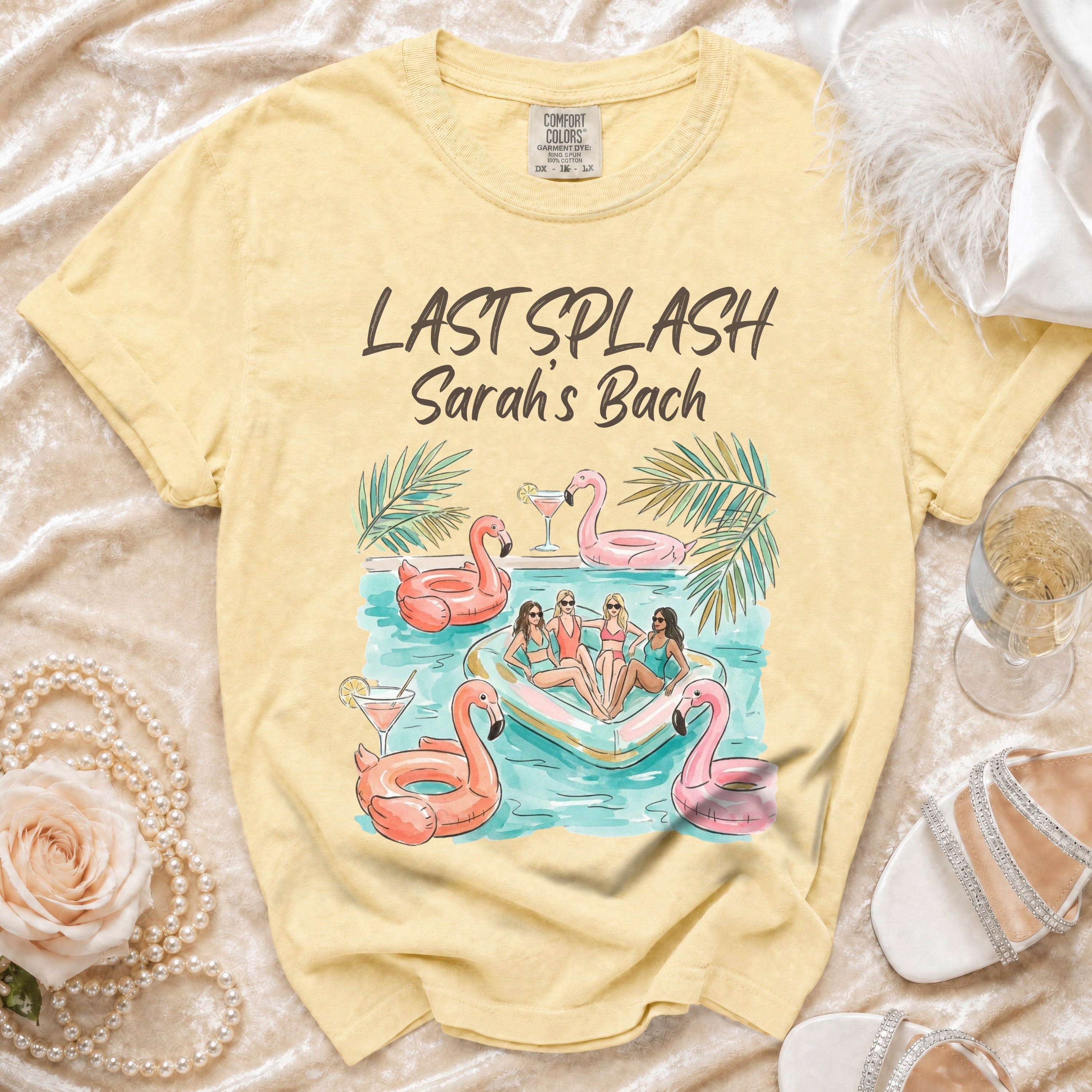 Yellow t-shirt with "Last Splash Sarah's Bach" text and illustration of people on an inflatable flamingo.