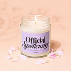 Burning candle with lavender label reading "Smells Like Official Spellcaster".