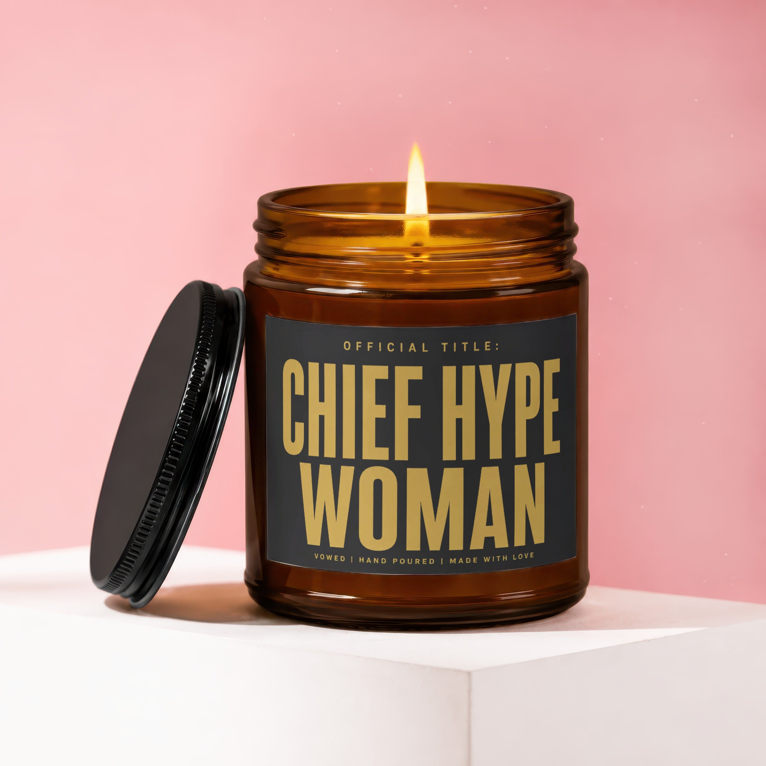 Amber jar candle with lit flame, black lid and label reading "Chief Hype Woman".