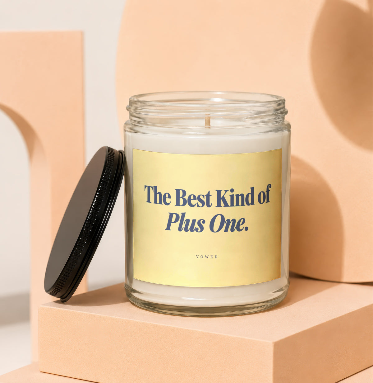 Glass candle with "The Best Kind of Plus One." text on label.