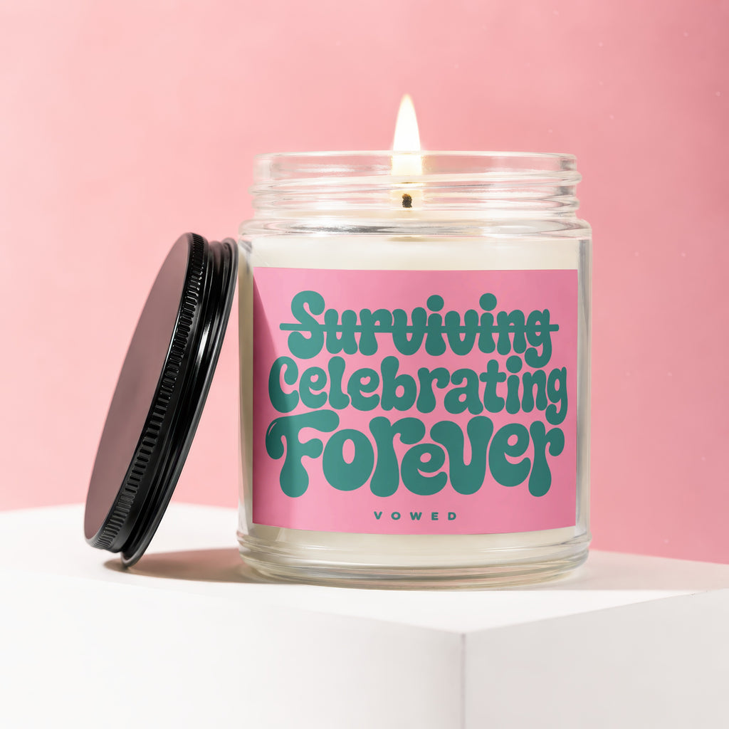 Glass candle with pink label that reads "Surviving Celebrating Forever Vowed."
