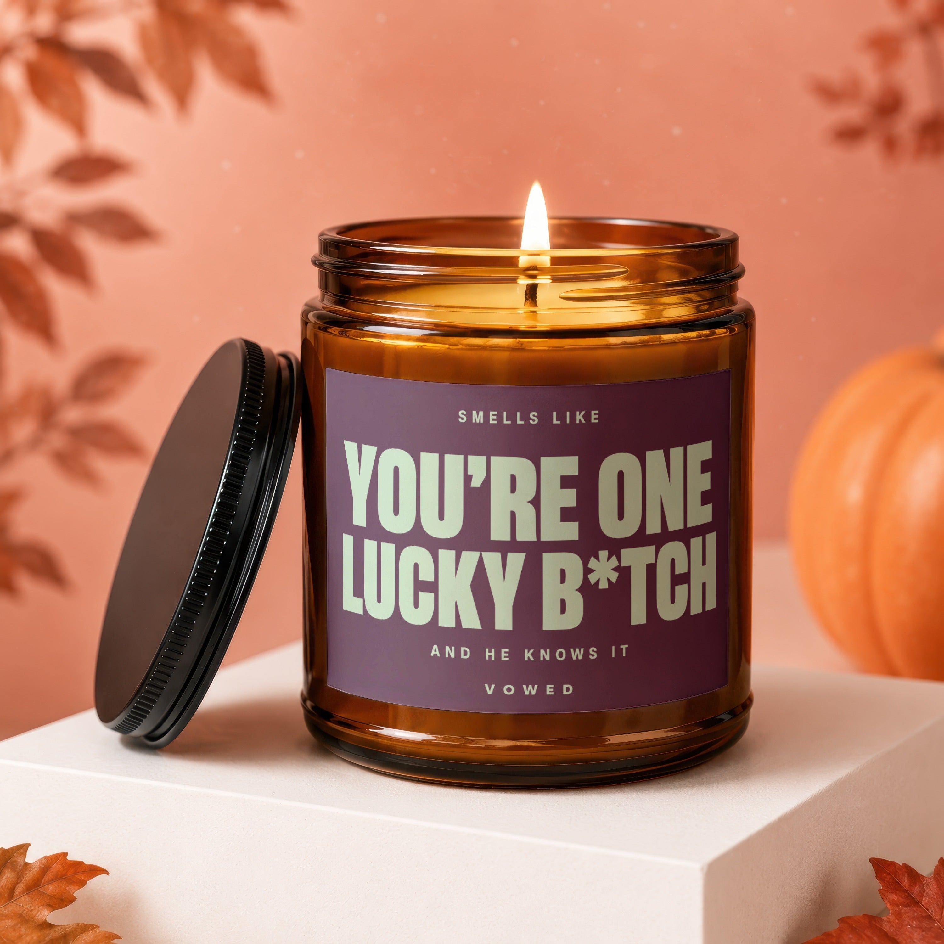 Amber glass candle with lid off, reads "You're One Lucky B*tch"