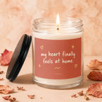 Glass candle with burning flame, reads "my heart finally feels at home."