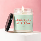 Jar candle with lid off, reading "A Little Sparkle, A Lot of Love."