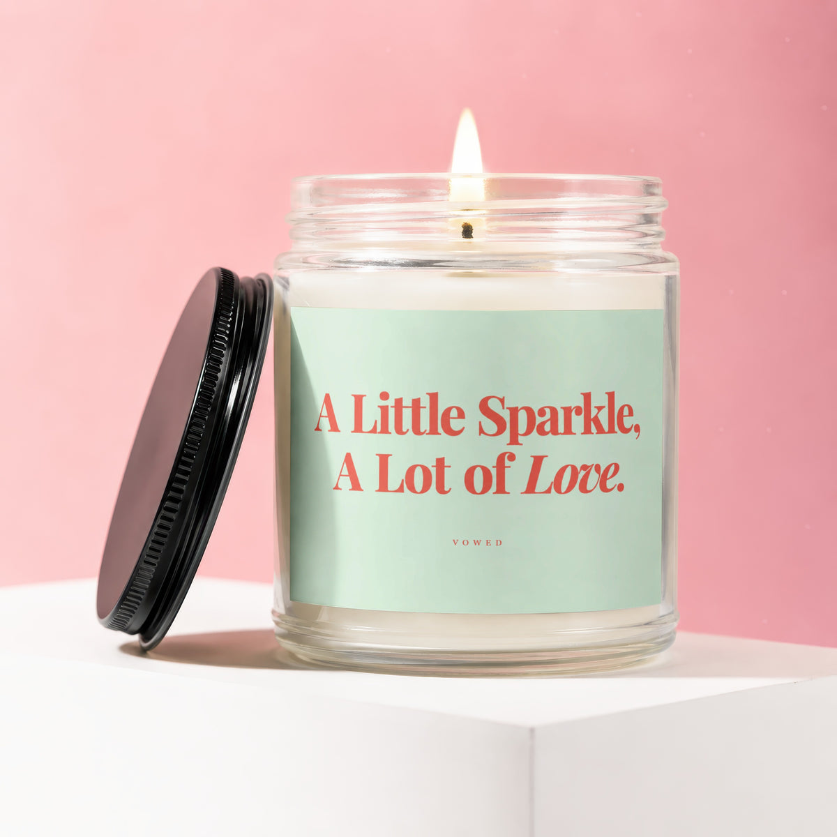 Jar candle with lid off, reading "A Little Sparkle, A Lot of Love."