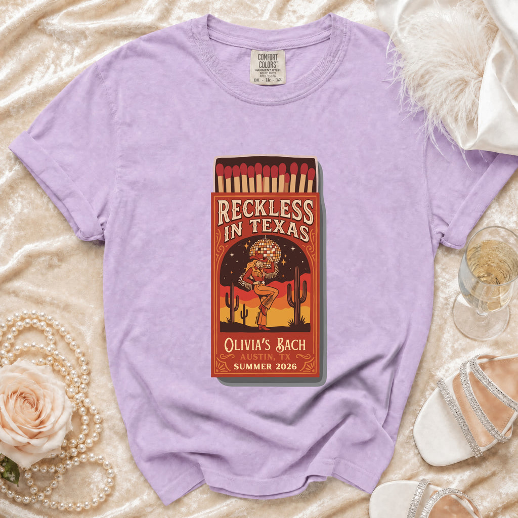 Purple t-shirt with "Reckless in Texas" matchbox graphic celebrating Olivia's Bach.