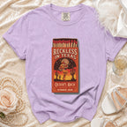 Purple t-shirt with "Reckless in Texas" matchbox graphic celebrating Olivia's Bach.