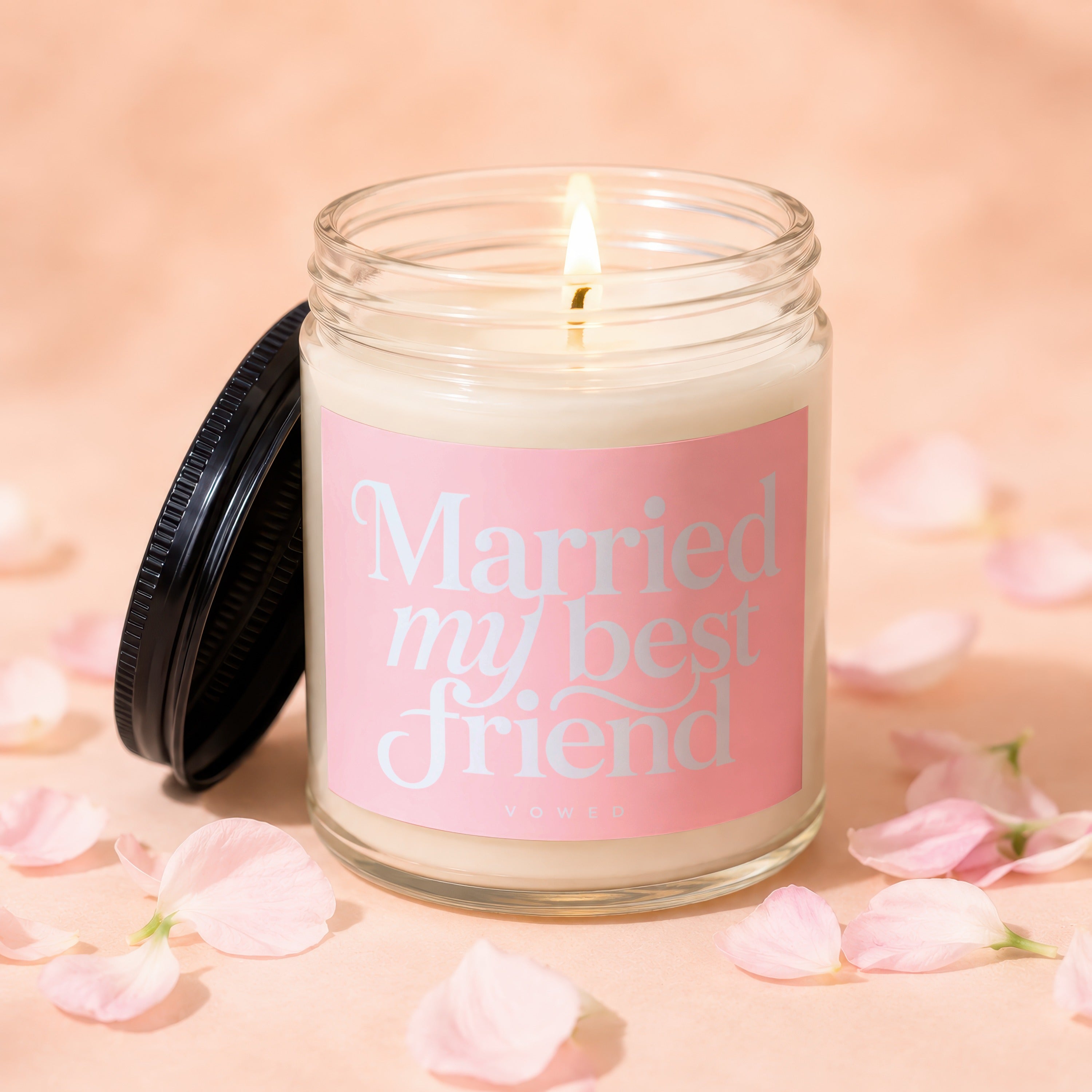 Lit candle in glass jar with pink label reading "Married my best friend" and "vowed."