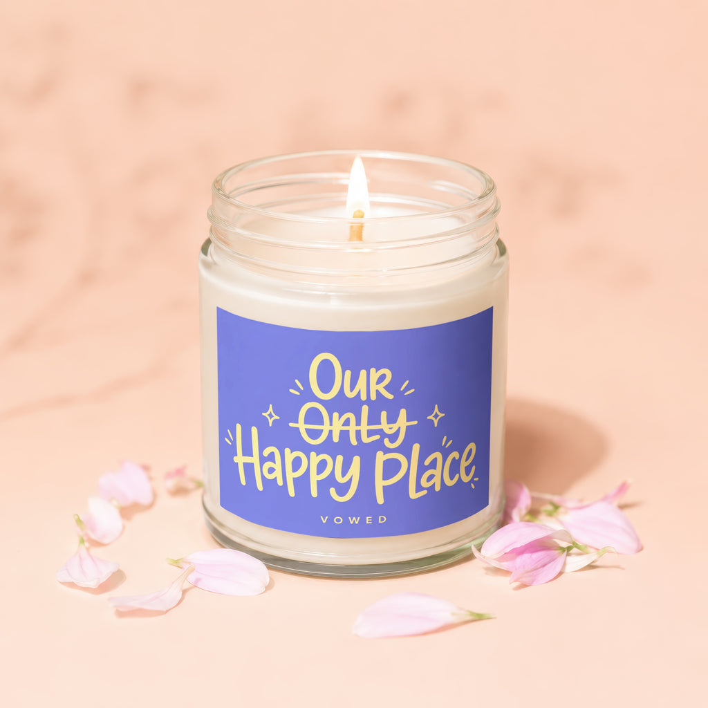 Glass jar candle with blue label reading "Our Only Happy Place VOWED".