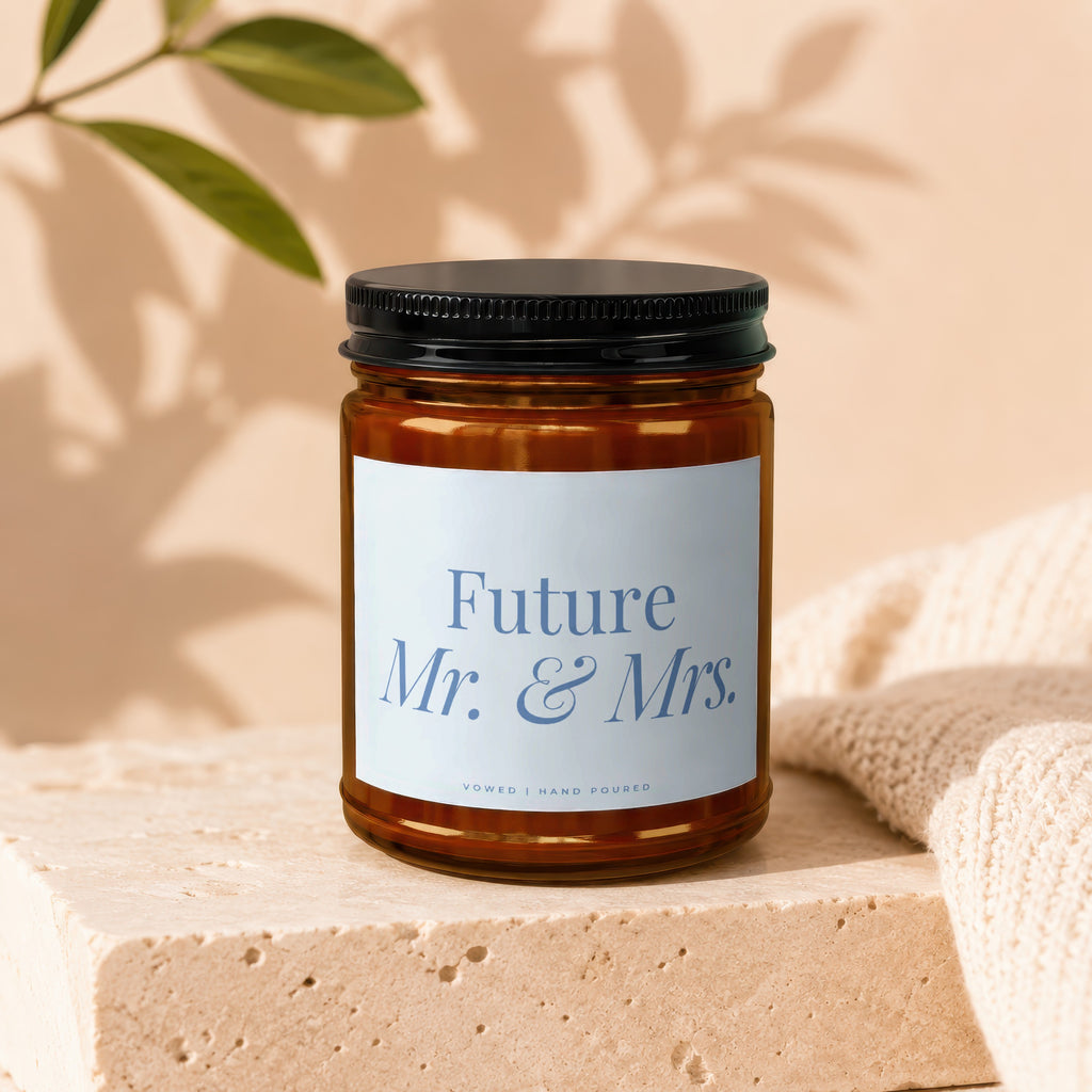 Amber jar candle with "Future Mr. & Mrs." text, set on stone and fabric.