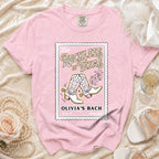 Pink t-shirt with "Reckless in Texas" and cowboy boots graphic.