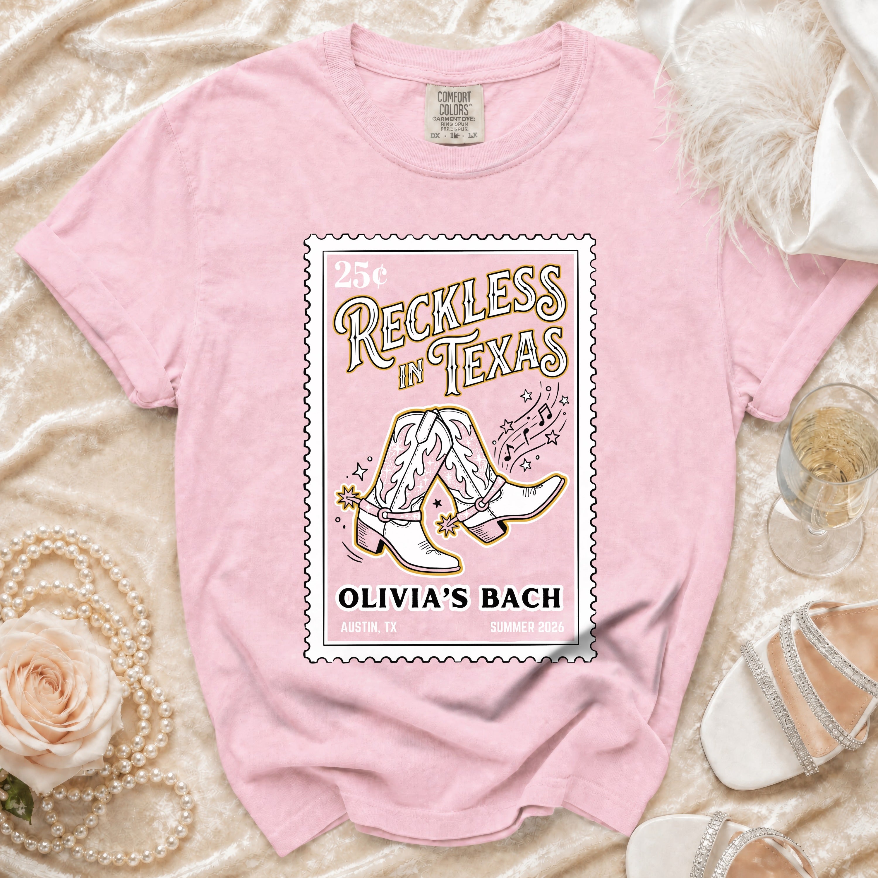 Pink t-shirt with "Reckless in Texas" and cowboy boots graphic.